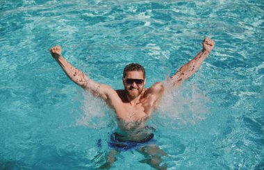 Havuz tatili. Havuzda mutlu bir adam. Yaz tatili. Güneş gözlüklü adam yüzme havuzunda dinleniyor..