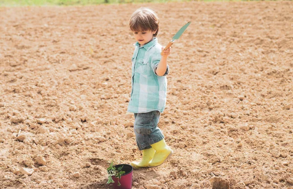 J'aime passer du temps à la ferme. Une routine de jardinage printanier. Jeux d'enfants dans le jardin de printemps. Portrait de jardinier enfant portant récolté à la ferme. — Photo