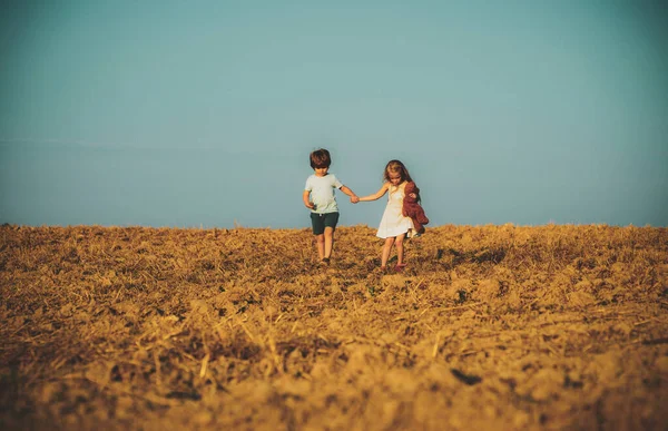 Vacker rolig dag för söta vänner i naturen. Barn har sommarglädje. Barn leker utomhus. Och samtidigt ha kul utomhus. Positiv liten flicka och pojke. Liten unge utomhus. — Stockfoto