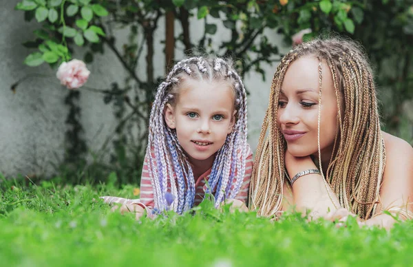 Portrait close-up happy smiling mother with her little daughter on grass. Mother and daughter enjoy and looking at the camera. Family holiday and togetherness. — Stock Photo, Image