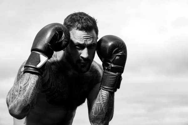 La boxe sportive. boxeur sportif combattant sur fond de ciel. Homme athlétique fort avec des gants de boxe poinçonnant. Punch de boxe. — Photo