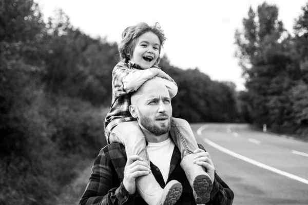 Pai e filho brincando ao ar livre piggyback. Caminhada em família no fundo do outono. Paternidade. — Fotografia de Stock