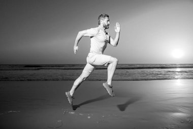 Gün batımında koşan adam. Sağlıklı bir adamın koşması ve dışarıda koşması. Erkek koşucu. Fit adam fitness modeli deniz kıyısında çalışıyor. Kumsalda koş. Spor koşusu.