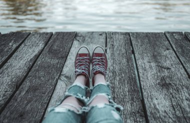 Çocuk kırmızı spor ayakkabılar içinde bir çocuk kampında dinleniyor. Şehir dışında Gölü manzaralı spor ayakkabı içinde genç. Kampında yaz tatilinde kaygısız tatil.