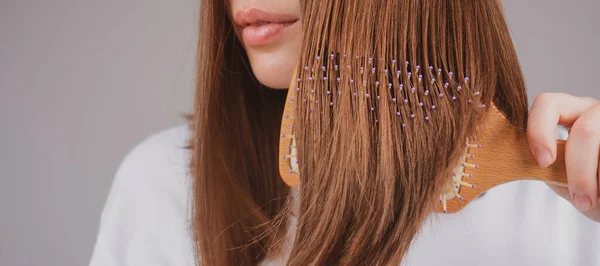 Closeup brunette hair lady combing hair with hairbrush comb, isolated. — Stock Photo, Image