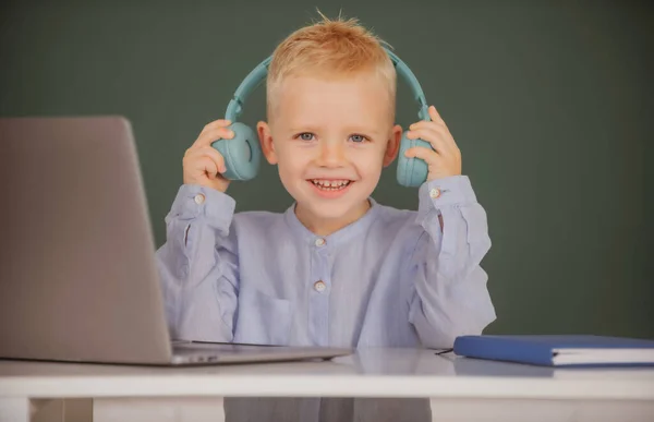 Dítě chlapec ve sluchátkách studovat online, dítě ve sluchátkách mít internetovou lekci. Den znalostí. — Stock fotografie