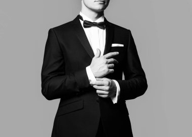 İş görünüşü. Kol düğmelerini tamir eden adam. Erkek giyimi modası. Siyah takım elbiseli beyefendi. Zarif ve şık kıyafetler..