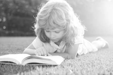 Dışarıda kitap okuyan sevimli bir çocuk. Çocuk parkta kitap okudu..