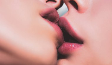 İki kadın öpüşüyor. Lezbiyen çift dudaklarını öpüyor. Seksi lezbiyen aşıklar ön sevişme. Kadınların öpüşen ağızlarına yakın çekim.