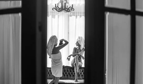 Dziewczyny robią sesję zdjęciową w luksusowym mieszkaniu. Seksowny fotograf z kamerą robiący zdjęcia przyjaciółce. Naga modelka. Relaks z najlepszymi przyjaciółmi na ślubie, wieczór panieński. — Zdjęcie stockowe
