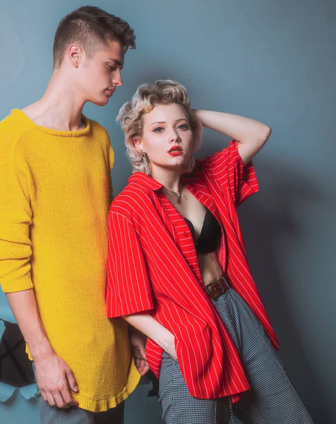 Prachtige vrouw met in rood shirt poseren met knappe brunette man in gele trui. Fashion portret mooi sexy paar. Commercieel ontwerp. Jongeren in jeans op een donkere achtergrond. Mode. — Stockfoto