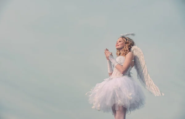 Charming curly little girl in white dress and wings - angel cupid girl. Portrait of a cupid little girl pray. Cherub. Cute teen cupid on the cloud - heaven background. Sweet angel girl. — Stok fotoğraf