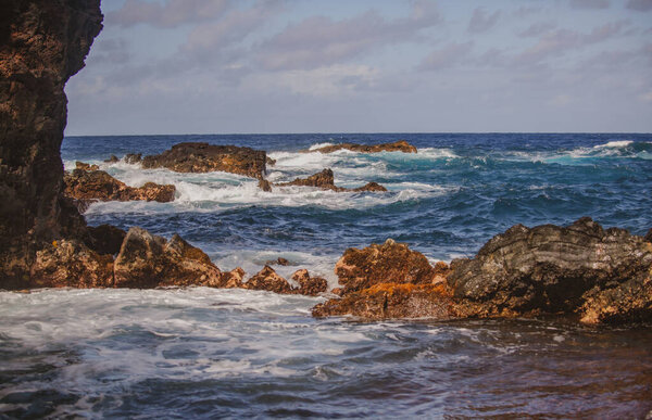 Скалистое побережье. Красивые бирюзовые воды моря. Океанские волны против прибрежных скал. Вид на океан. Прекрасный летний морской пейзаж.