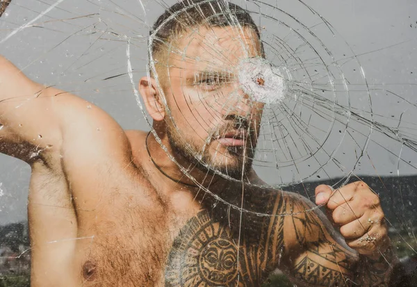 Sexy gangster man. Dangerous criminal, hooligan guy on cracked bullet glass. — Stock Photo, Image