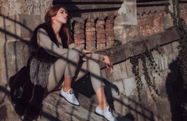 Zengin kıyafetli ve tüylü kürklü şık bir manken. Şık vücutlu ve uzun siyah saçlı güzel bir genç kız pofuduk gerçek kürk mantoyla şehir caddesinde yürüyor. Lüks moda konsepti.