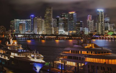 Günbatımında Miami Florida, aydınlık binaların ufuk çizgisi ve Macarthur Causeway köprüsü. Miami şehir merkezi.