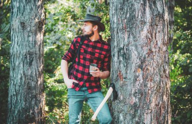 Sıkı çalışmadan sonra dinleniyor. Tarım ve ormancılık teması. Ağaç kesiyorum. Yasadışı kütükleme bugün de devam ediyor. Ormanın yakınlarında baltası olan yakışıklı bir genç..