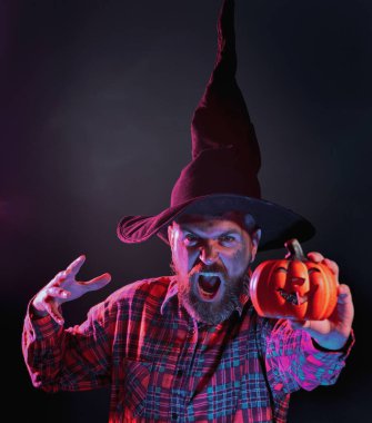 Karanlık arka planda korkunç yüzü olan cadılar bayramı adamı. Cadılar Bayramı, bayram kutlaması. Korkunç suratlı korkunç adam Balkabağı kafalı Jack Lantern 'i tutuyor.