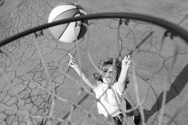 Cute little boy child in basketball uniform jumping with basket ball for shot. Happy child playing basket ball on playground. — Stock Photo, Image