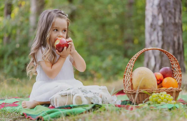 Παιδί στο πικ-νικ το φθινόπωρο τρώει μήλο. Μικρό κορίτσι στο πάρκο του φθινοπώρου. — Φωτογραφία Αρχείου