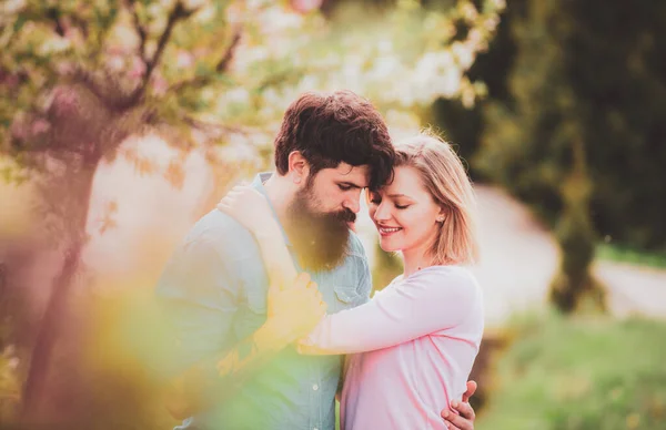 Hübsche Frau und schöner Mann, die im Frühlingspark spazieren gehen und die schöne Frühlingsblütennatur genießen. — Stockfoto