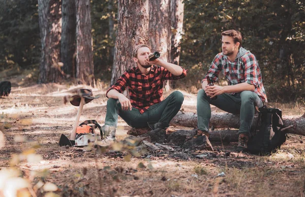 Vacation weekend picnic camping and hiking. Friendship and leisure concept. Summer vacation. Two friends lumberjack worker sitting in the forest with beer. Tourism concept. — Stock Photo, Image