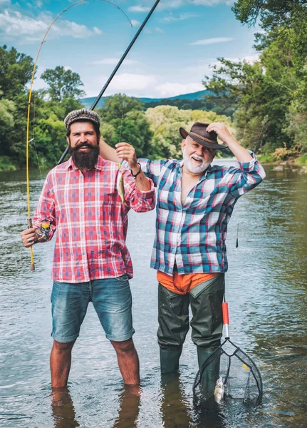 Uomo che pesca. Uomini che pescano nel fiume durante la giornata estiva. Padre e figlio pescano. Barra di mosca e oscillazione con una trota marrone da una corrente . — Foto Stock