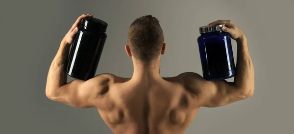 Muscular man with vitamin supplements. Strong man hold supplement protein bottles. Vitamin diet and sport nutrition. — Stock Photo, Image