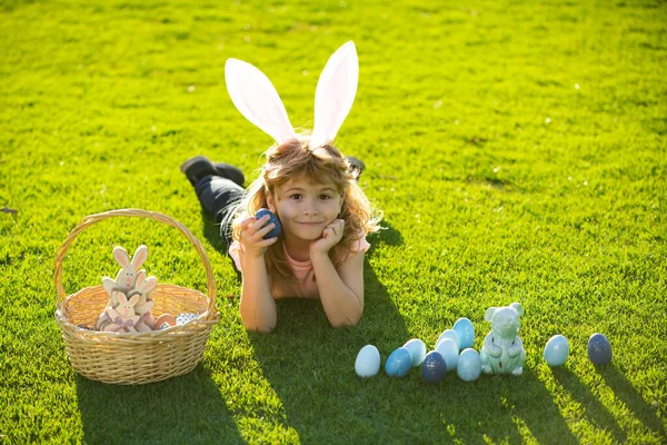 Jongetje met paaseieren en konijnenoren op gras. Vrolijk Pasen. — Stockfoto