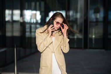 Modaya uygun bir iş kadını sokakta telefonla konuşuyor. Moda tarzı..