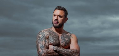 Ciddi yüzlü yakışıklı bir adamın portresi. Dramatik gökyüzünde açık hava erkek portresi.