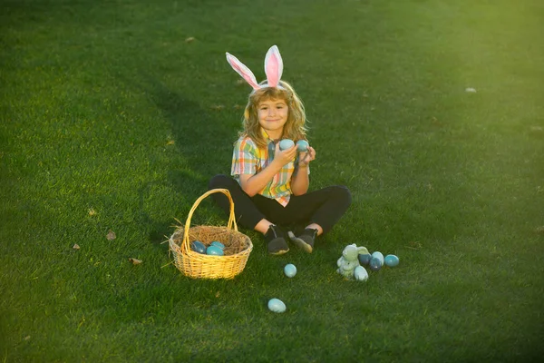 Κουνελάκια με αυτιά κουνελιού. Κυνήγι πασχαλινών αυγών στον κήπο. Παιδί που παίζει στον αγρό, κυνηγάει πασχαλινά αυγά. — Φωτογραφία Αρχείου