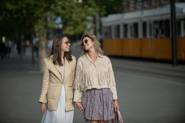 Dos mujeres felices y emocionadas caminando juntas en la calle. Chicas de moda felices en la ciudad. Jóvenes mujeres alegres expresando positividad, vacaciones con emociones alegres, buen humor. —  Fotos de Stock