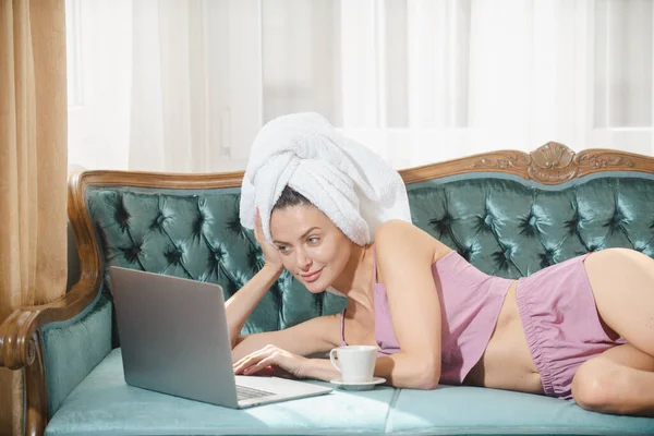 Lavoro da casa, freelance e stile di vita concetto. Belle donne con caffè e laptop in accappatoi e asciugamani in camera da letto. — Foto Stock