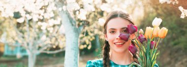 Bahar kadını pankarta karşı. Çiçekli güzel bir bahçıvan kız. Ev bahçesinde sebze eken, açık hava aktivitelerini gevşeten komik kız. Bahar çiçeği arkaplanı.