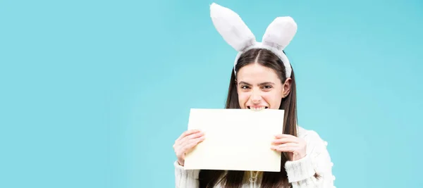 Easter banner with bunny woman. Model dressed in costume Easter bunny on isolated background hold paper for text. Bunny girl portrait. — Stock Photo, Image