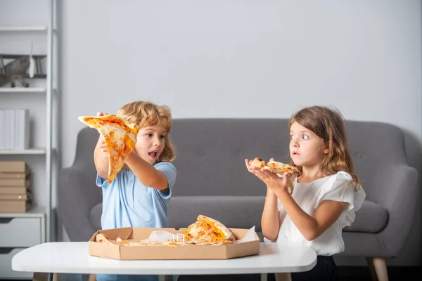 Pizza yiyen komik çocuklar. Küçük çocuklar arkadaşlar, erkek ve kız pizza yer.. — Stok fotoğraf