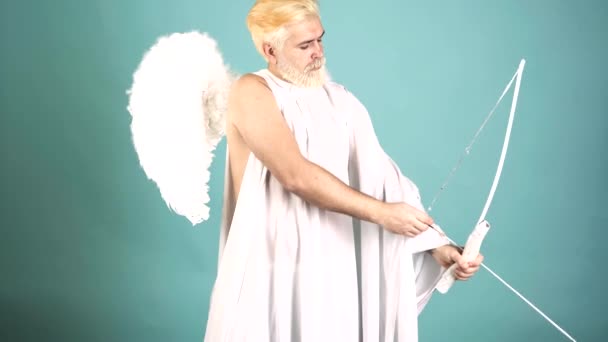 Funny cupid, handsome guy on valentine day with bow arrow shooting. Love concept. Handsome crazy fun angel. Valentines Day. — Stockvideo