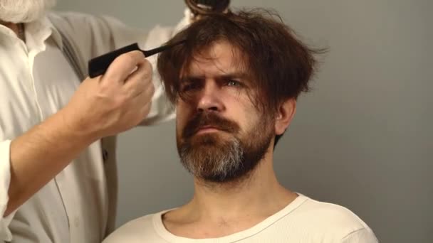 Cabeleireiro com pente pentear o cabelo do homem na barbearia. Barbeiro fazendo corte de cabelo para homem atraente na barbearia. — Vídeo de Stock