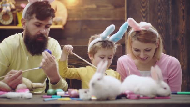 Uova di Pasqua disegno concetto. La famiglia pasquale di figlio di bambino di padre di madre dipinse uova, indossando orecchi di coniglio. Famiglia Festeggiamo la Pasqua con i bambini a casa, divertenti genitori coniglietti pasquali. Vacanze primaverili in famiglia. — Video Stock