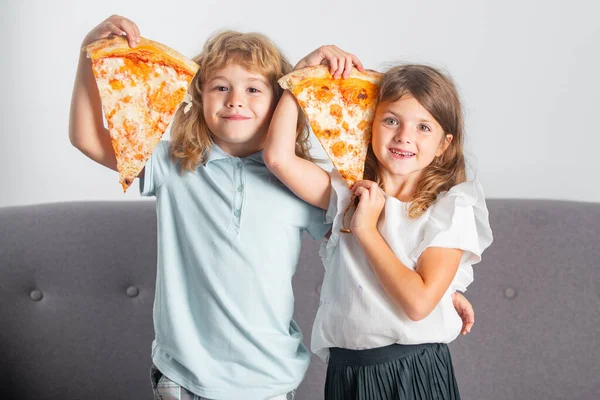 Pizza ve çocuklar, çocukların elinde pizza dilimleri. Çocuklar peynirli lezzetli fast food pizzası yiyorlar. Mutlu çocuklar pizza dilimlerini yüzlerine yakın tutuyorlar. Eğlenceli çocuklar birlikte eğleniyorlar.. — Stok fotoğraf