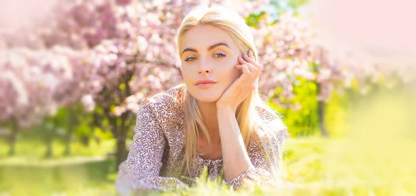 Cara de mujer primavera para estandarte. Hermosa chica en flores rosadas en el parque de flores de verano. — Foto de Stock