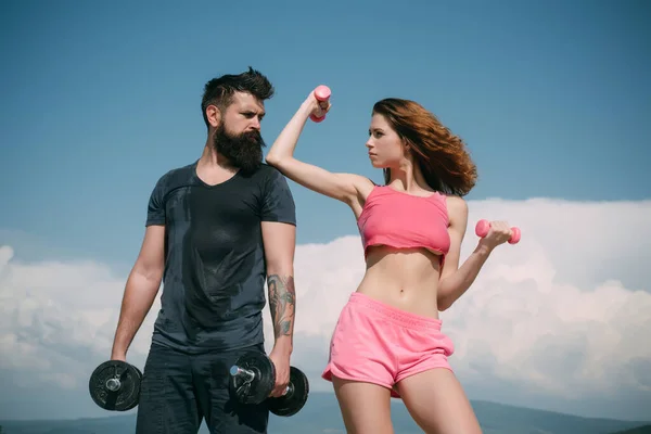 Ajuste sexy pareja en el fondo del cielo con mancuernas. Concepto fitness. Entrenamiento de pareja deportiva con mancuerna. Estilo de vida saludable coupl. —  Fotos de Stock