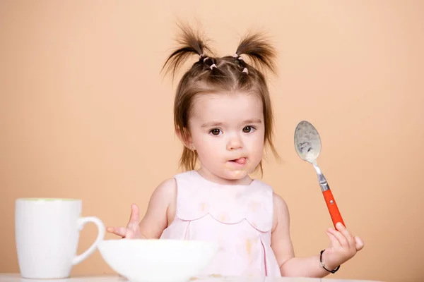 Kind eet gezonde voeding, babyvoeding. Baby 's eten met lepel. Grappig baby meisje met lepel op studio, geïsoleerd. — Stockfoto