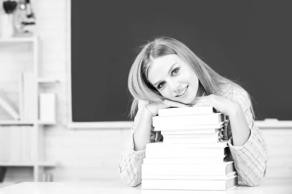 Primer plano retrato de la joven estudiante atractiva feliz con libros en pizarra en el aula. — Foto de Stock