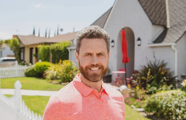 Glücklicher Mann, der vor dem Haus steht. Geschäftskonzept. Porträt eines gutaussehenden Geschäftsmannes mit selbstbewusstem Gesicht. Hintergrund der Vorstadt. — Stockfoto