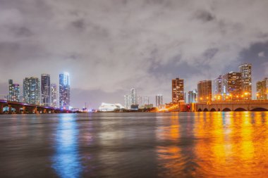 Miami, Florida şehir merkezi Biscayne Körfezi 'nde. Günbatımında şehir gökdelenleri ile Panorama ve yansıma ile deniz üzerinde köprü.