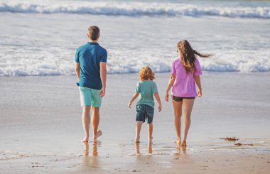 Kumsalda mutlu bir aile. İnsanlar yaz tatilinde eğleniyor. Baba, anne ve çocuk mavi denizde. Tasasız aile kavramı. Bali 'de çocuklu aileler rahatlar..