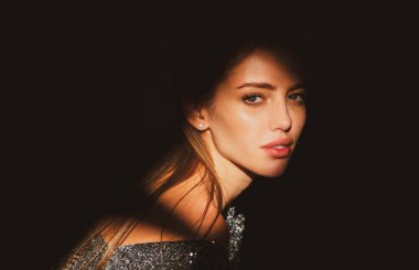 Stüdyoda poz veren genç bir kadın. Işık ve gölge. Yüzünde koyu renk ışık olan güzel bir kadının moda portresi. Kızların yüzü gölgeli, çekici kadın model..