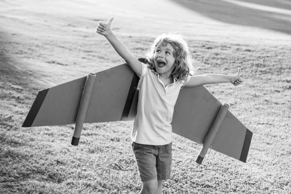 Un niño emocionado jugando al aire libre. Líder de niños y ganador, arranque de éxito. niño asombrado jugar con juguete jetpack alas superhéroe en parque. —  Fotos de Stock